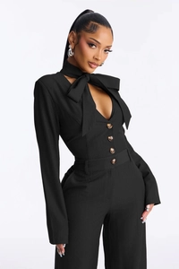 Detail of elegant black pinstripe jumpsuit with large bow tie and amber buttons