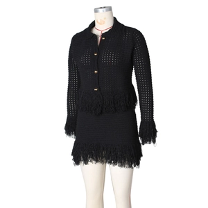 Detail of black crochet knit set showing gold buttons and fringe trim on the sleeve and hem