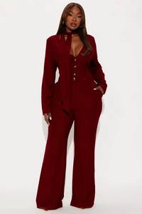 Detailed view of dark wine red ribbed fabric texture and elegant bow tie on a jumpsuit