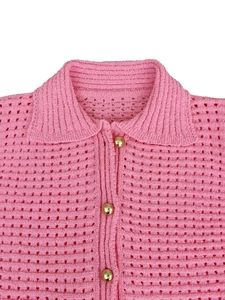 Detailed macro view of pink hollow knit fabric and polished gold metallic buttons