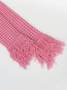 Close-up of pink knit scarf featuring intricate hollow crochet weave and long fringe tassels