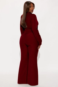 Close-up of deep red ribbed knit fabric on wide-leg jumpsuit showing texture and fit