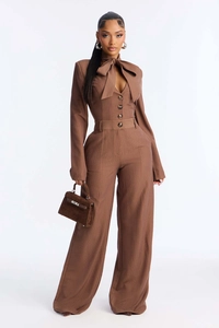 Close-up of brown pinstripe jumpsuit featuring a large bow tie and button-up front