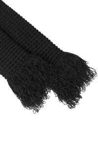 Close-up of black knitted fabric texture and long fringe tassels on garment hem