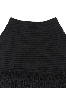 Detailed view of black knitted fabric featuring ribbed edges and dense long fringe trim