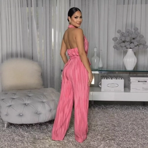 Pink halter backless wide leg jumpsuit in pleated fabric with a matching waist belt
