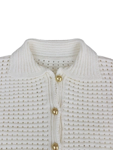 Detail of white hollow knit polo shirt showing textured fabric and gold metal buttons