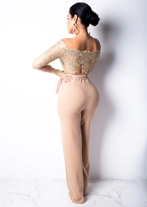 Detail of elegant gold lace embroidery on the off-shoulder neckline of an apricot jumpsuit