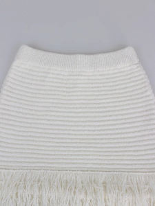 Detailed close-up of white knit pencil skirt featuring ribbed waist and fringe hem details