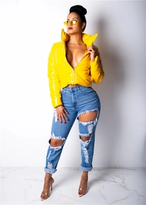 Détail d'une doudoune en similicuir jaune brillant et d'un jean délavé style streetwear