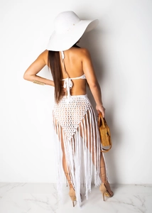 Macro detail of white crochet bikini with long fringe tassels and intricate hand-knit patterns