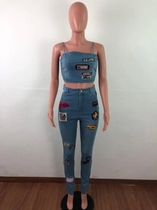Detail of blue denim set featuring vintage embroidered patches and cropped tank top style