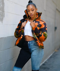 Close-up detail of street style camouflage puffer jacket with two-tone patchwork jeans