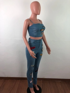 Detail of light blue denim set featuring vintage cartoon patches and embroidery on fabric