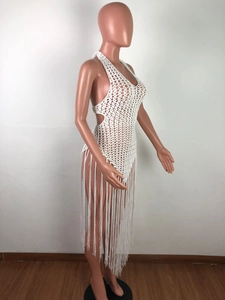 Detail of white crochet beach dress featuring hollow mesh texture and long tassels