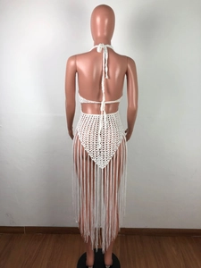 Detail of white crochet beach dress featuring intricate hollow mesh and long fringe tassels