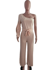 Detail of one-shoulder jumpsuit with cutout long sleeve and waist bow tie in beige