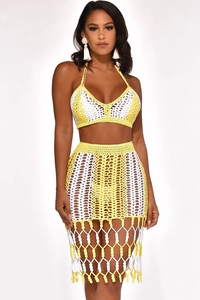 Detail of crochet knit two-piece set featuring yellow and white patterns and fringe hem