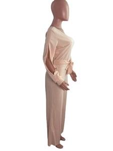 Detail of light peach jumpsuit featuring long slit sleeves and a self-tie waist bow