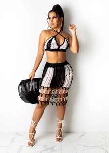 Detail of crochet knit two-piece set featuring hollow mesh skirt and braided fringe hem