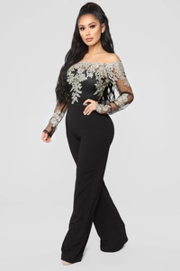 Close-up of elegant silver lace embroidery on black off-the-shoulder wide-leg jumpsuit