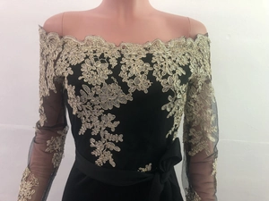 Detailed view of gold floral lace embroidery on black mesh long sleeves and off-shoulder