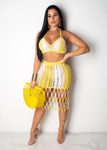 Detail of yellow and white crochet beach set featuring halter top and fringed midi skirt
