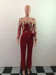 Detail of red off-shoulder jumpsuit featuring intricate gold lace floral embroidery on sleeves