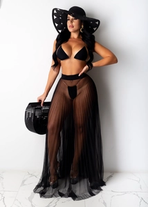 Detalle de falda playera de malla negra combinada con un elegante traje de baño de tres piezas