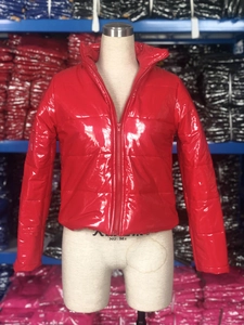 Détail de la doudoune rouge brillante avec col montant et texture en similicuir verni