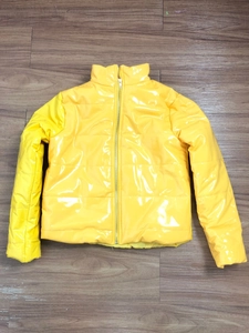 Gros plan détaillé d'une doudoune jaune brillante avec finition laquée et zip argenté