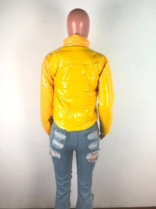 Détail de la doudoune jaune brillante en PU et du jean bleu délavé avec déchirures