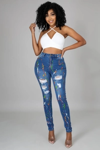Dettaglio dei jeans skinny da donna con schizzi di vernice colorati e strappi sulle ginocchia