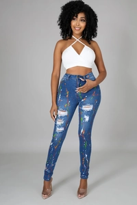 Dettaglio di jeans skinny a vita alta con schizzi di vernice colorata e strappi denim