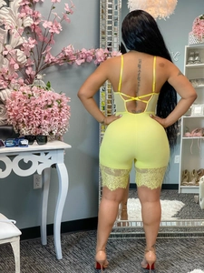 Detail of yellow lace romper featuring cross-back straps and floral lace hem on shorts