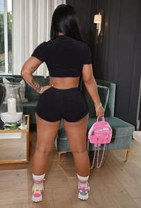 Vue arrière d'un ensemble crop top et short en velours noir dans un salon moderne