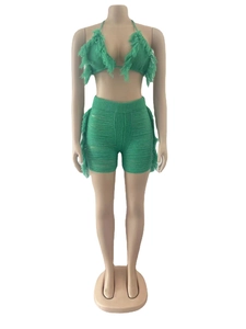 Dettaglio del set da spiaggia in maglia verde con top bikini a frange e pantaloncini a vita alta