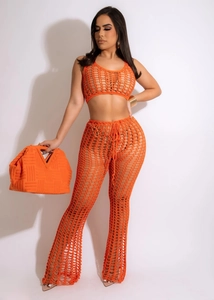 Detail of orange crochet two-piece set featuring hollow mesh knit top and flared pants