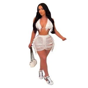 Dettaglio di un set bikini bianco all'uncinetto con pantaloncini a frange e top allacciato