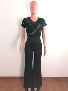 Close-up of asymmetrical green sequin bodice and sheer mesh paneling on the jumpsuit