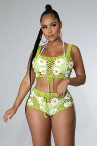 Detalle de un conjunto de ganchillo verde con motivos florales de margaritas hechos a mano