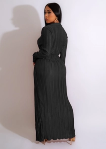 Détail de la robe longue noire plissée à manches longues avec texture verticale et fente latérale