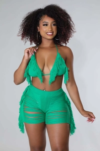 Dettaglio di un set due pezzi in maglia verde con nappe all'uncinetto e stile spiaggia
