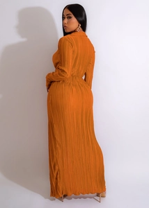 Détail d'une robe maxi plissée orange montrant des plis verticaux fins et une taille ajustée