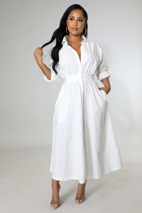 Détail d'une robe chemise blanche à manches longues avec taille cintrée et jupe plissée