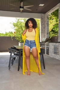 Detail of long yellow crochet cardigan with hollow mesh texture over denim shorts