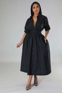 Détail d'une robe chemise noire à manches longues avec col boutonné et plis à la taille