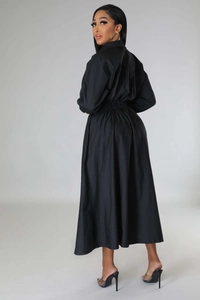 Détail de la robe longue noire à manches longues avec taille ajustée et jupe plissée