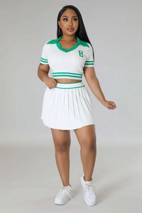 Detail of white knit polo top with green striped hem and high-waisted pleated mini skirt