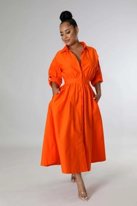 Détail des plis à la taille et des poches sur une robe chemise orange à manches longues